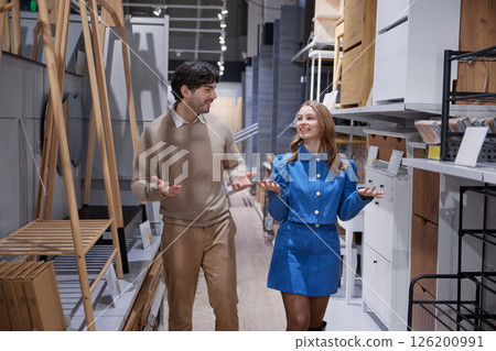 Couple exploring furniture options together in contemporary home goods store with various pieces 126200991
