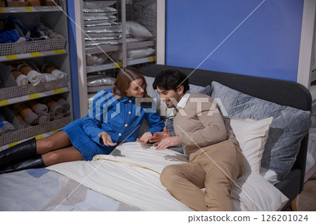 A loving couple is happily relaxing on their bed within a beautifully designed modern bedroom setup A loving couple is happily relaxing on their bed within a beautifully designed modern bedroom setup 126201024