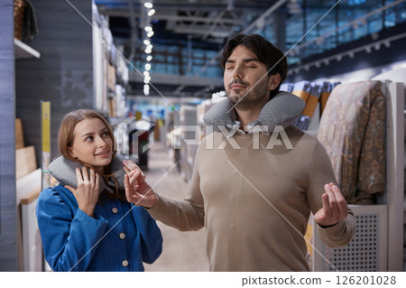 Couple happily enjoying testing out cozy neck pillows in a stylish and modern retail environment Couple happily enjoying testing out cozy neck pillows in a stylish and modern retail environment 126201028