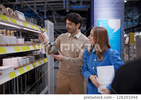A cheerful woman joyfully embraces soft textiles as a man evaluates various products in a home store A cheerful woman joyfully embraces soft textiles as a man evaluates various products in a home store 126201048