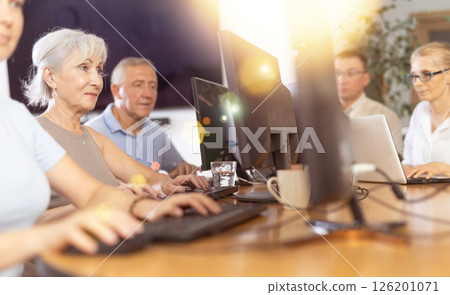 Side view of mature people while studying in computer lab in nursing home 126201071