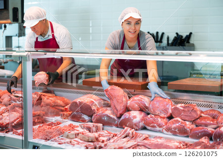 Adult man and young woman sellers lay out beef in butcher shop 126201075