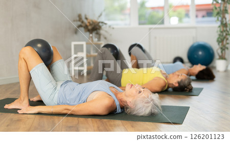 Group of elderly woman doing pilates with soft ball in studio 126201123