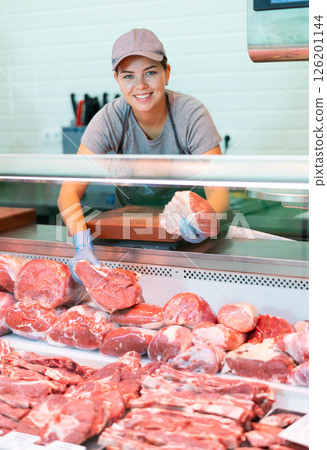 Young woman seller lays out beef in butcher shop Young woman seller lays out beef in butcher shop 126201144
