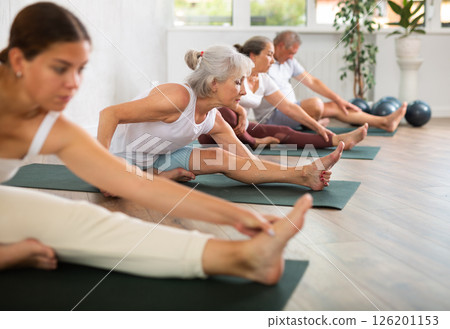 Elderly woman doing yoga on mat in studio 126201153