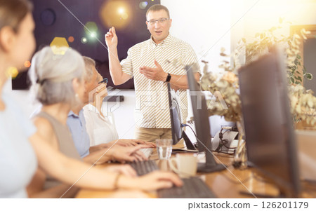 Male teacher teaching elderly people how to use computer Male teacher teaching elderly people how to use computer 126201179