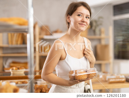 Girl in casual clothes chooses fresh cookie for breakfast in bakery 126201180