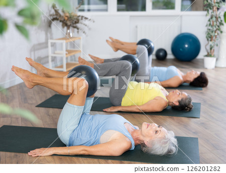 Group of elderly woman doing pilates with soft ball in studio 126201282