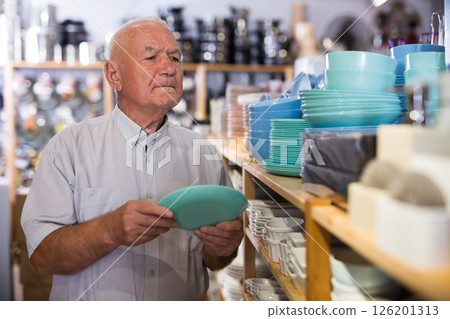 Ordinary male buyer chooses plates in tableware store 126201313