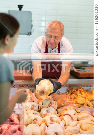 Adult man butcher sells chicken in butcher shop Adult man butcher sells chicken in butcher shop 126201330