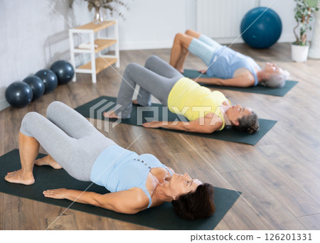 Old woman practicing bridge pose of yoga in training room during fitness classes Old woman practicing bridge pose of yoga in training room during fitness classes 126201331