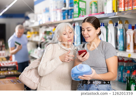Young girl and elderly woman scanning QR code on detergent in store 126201359