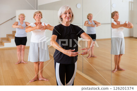Aged woman practicing ballet dance moves in choreographic studio 126201374