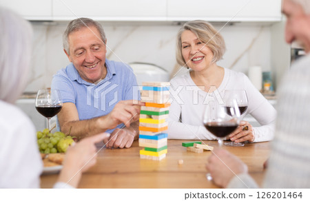 Group of four mature friends is playing board game with wooden blocks in kitchen 126201464