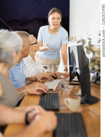 Mature people listen attentively to female teacher during computer teaching lesson in nursing home Mature people listen attentively to female teacher during computer teaching lesson in nursing home 126201490