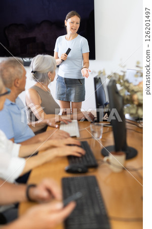 Female tutor teaching group of seniors in computer workshop 126201497