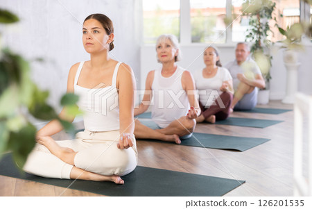 Women of different years doing yoga on mat in fitness studio Women of different years doing yoga on mat in fitness studio 126201535