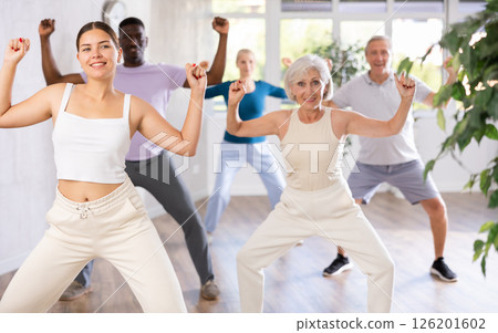 Female instructor teaches mature students of dance class basic movements of hip hop dance 126201602