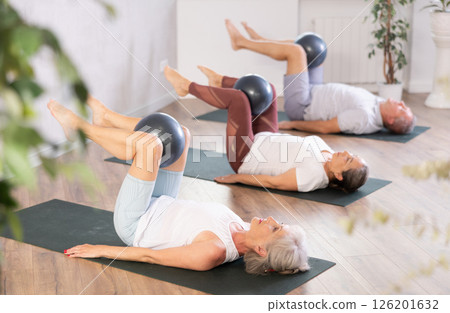 Group of elderly people doing pilates with soft ball in studio Group of elderly people doing pilates with soft ball in studio 126201632