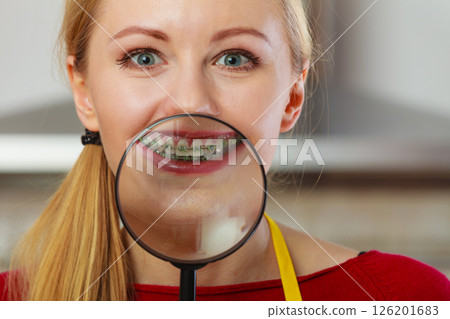 Happy woman showing her braces in magnifying glass 126201683