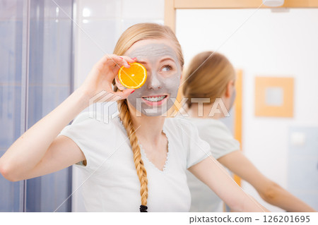 Happy young woman having face mask holding kiwi 126201695