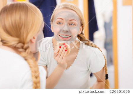 Woman removing mud facial mask with sponge Woman removing mud facial mask with sponge 126201696