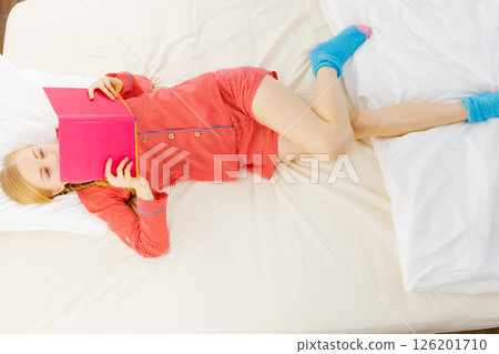 Woman relaxing in bed reading book 126201710