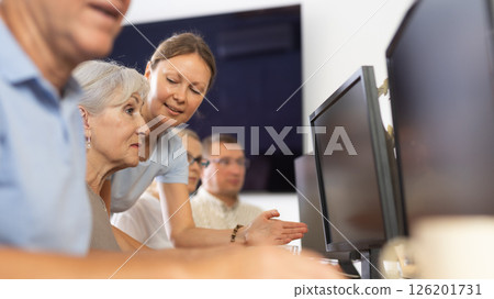 Mature people listen attentively to female teacher during computer teaching lesson in nursing home 126201731