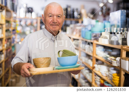 Senior man customer holding purchases and walking in household goods store 126201830