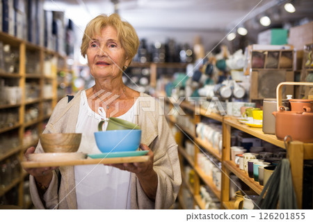 Senior woman customer holding purchases and walking in household goods store 126201855