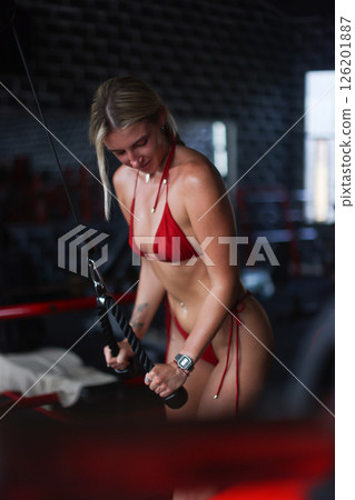 A dedicated fitness enthusiast is training hard at the gym while sporting a stylish red outfit 126201887
