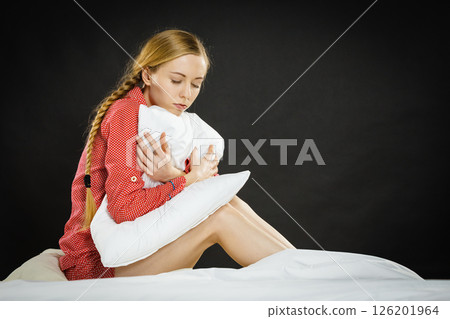 Sad depressed girl in bed gripping pillow 126201964