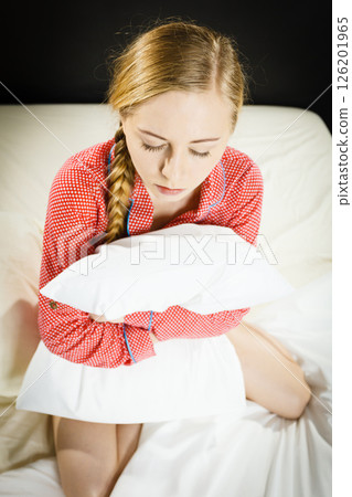 Sad depressed girl in bed gripping pillow 126201965