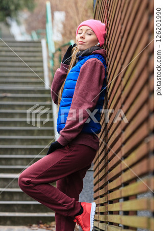 Woman wearing warm sportswear relaxing after exercising Woman wearing warm sportswear relaxing after exercising 126201990