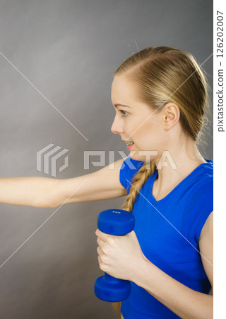 Teenage woman working out at home with dumbbell 126202007