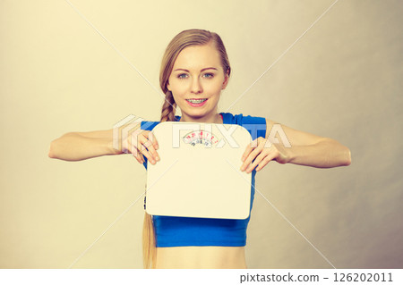 Teenage woman holding bathroom scale machine 126202011