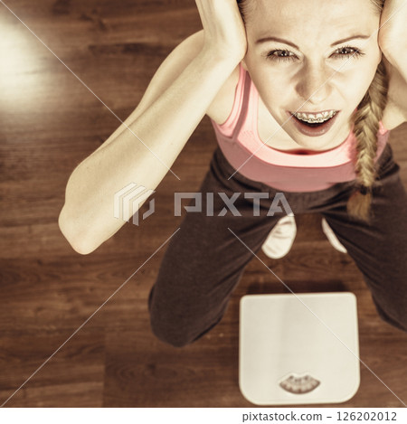 Scared woman on bathroom scale machine 126202012