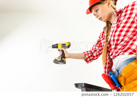 Woman using drill on ladder 126202057