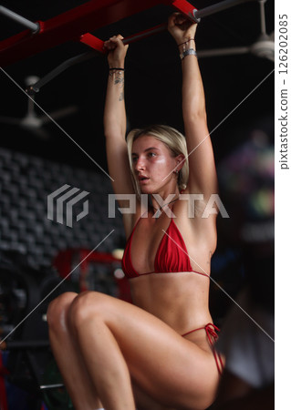 A Fitness Model Wearing a Stunning Red Bikini Training Vigorously at the Gym Environment 126202085