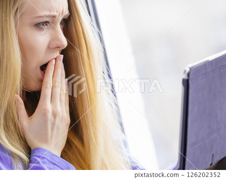 Shocked girl watching on tablet 126202352