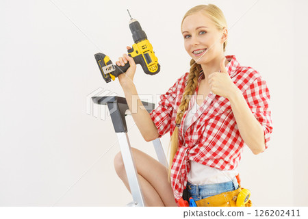 Woman on ladder using drill 126202411