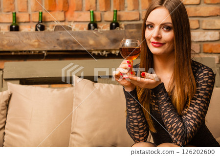 Woman tasting wine in rural cottage interior 126202600