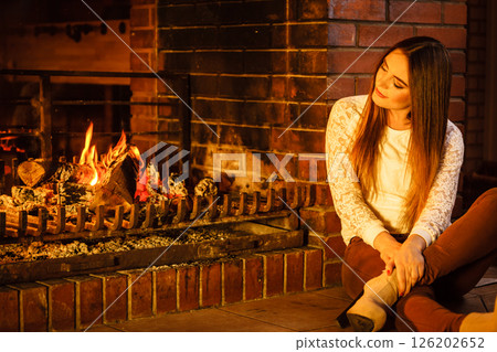 Woman relaxing at fireplace. Winter home. 126202652