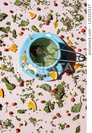Teacup with Brewing Herbal Tea Surrounded by Scattered Dried Herbs, Berries and Orange Slices. Healthy Drink and Wellness Concept. 126202817