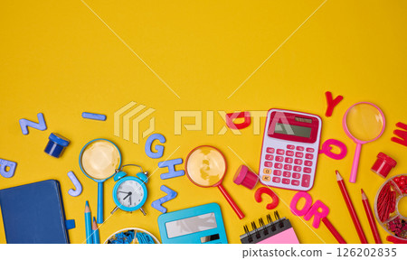 Colorful school supplies, learning items calculators, letters, tools, and stationery scattered on a vibrant yellow background. Education and back to school concept 126202835
