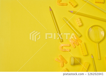 Assortment of yellow stationery and creative items scattered on a yellow background. Pencil, marker, building brick, letter, magnifying glass. Education or art concept 126202841