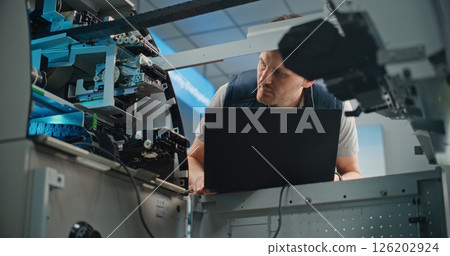 Male Worker Conducting Diagnostics of ATM Machine Using Laptop Male Worker Conducting Diagnostics of ATM Machine Using Laptop 126202924