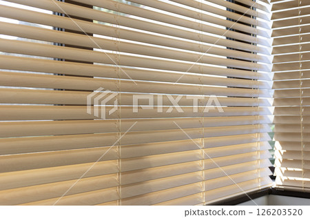 Light filtering through wooden blinds in cozy indoor space during daylight hours 126203520