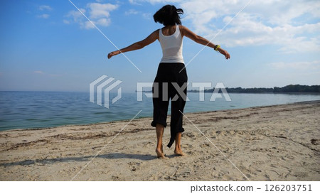 Beautiful lady walking on sandy beach near shoreline at sunny day. Happy adult woman turning around near coastline. Carefree female enjoying rest at seaside. Concept of summer vacation or holiday Beautiful lady walking on sandy beach near shoreline at sunny day. Happy adult woman turning around near coastline. Carefree female enjoying rest at seaside. Concept of summer vacation or holiday 126203751
