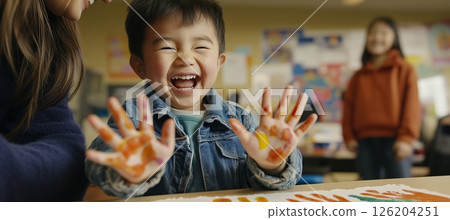 Parent guides child in creating a colorful handprint painting in a cheerful classroom setting 126204251